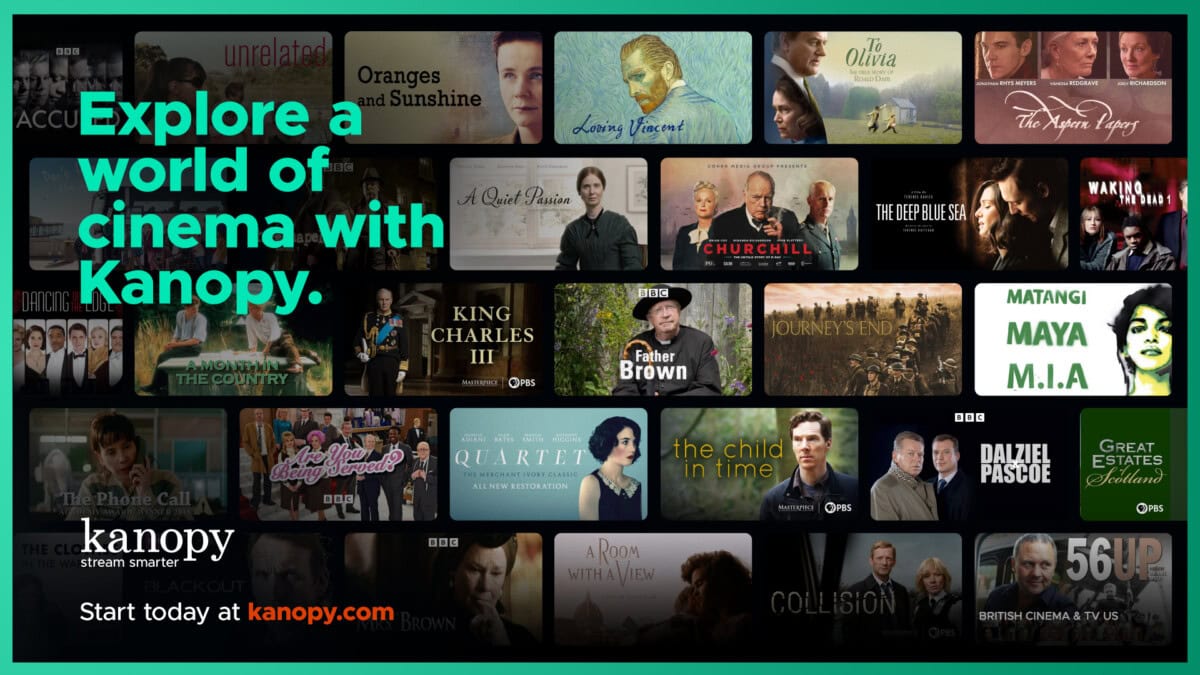 A red brick library building with columns and arched windows stands behind a snowy lawn. In the foreground, a sign displays the Wilton Library name, hours, and website. Snow is falling.